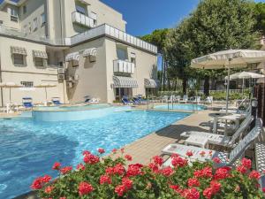 una piscina en un hotel con mesas, sillas y flores en New Hotel Chiari en Cervia