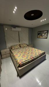 a bedroom with a bed with a floral comforter at Apartment in Bahria Town Lahore in Lahore