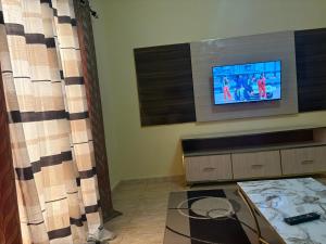 a living room with a tv and a curtain at Ouest foire in Dakan