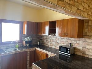 a kitchen with wooden cabinets and a microwave at Ouest foire in Dakan +12 photos