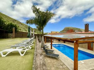 Una fila de tumbonas junto a una piscina. en Villa El Guanche, en Gáldar
