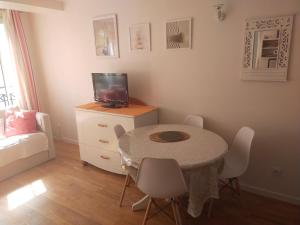 a small room with a table with chairs and a television at Le Bassin à vos pieds avec T2 Élégant entre Plage et Hyper Centre in Arcachon