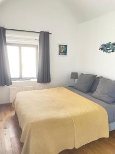 a bedroom with a bed with a yellow blanket on it at Entre terre et mer in Montfarville