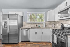 a kitchen with stainless steel appliances and white cabinets at 3 Bedroom House with Firepit St. Peters, MO in Saint Peters