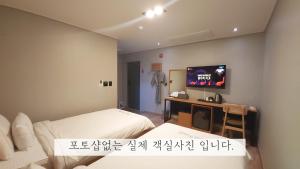 a room with two beds and a tv on the wall at Sea Star Hostel in Yeosu