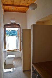 a bathroom with a toilet and a window at The Village Hideaway - Traditional Stone House in Kissamos