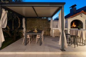 un patio con tavolo, sedie e camino di VILLA TUGARKA private pool, fitness, play-house, great for families, max 6 per. a Tugare