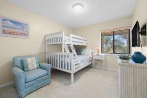 una camera con un letto a castello bianco e una sedia di Beachfront Aldea 6 a Clearwater Beach Altre 40 foto