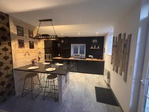 a kitchen with a island with two bar stools at Le tilou in Fontenay-le-Pesnel