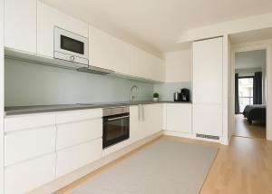 a white kitchen with white cabinets and a sink at City Home Finland Big Luxury Suite - Spacious Suite with Own SAUNA, One Bedroom and Furnished Balcony next to Train Station in Tampere