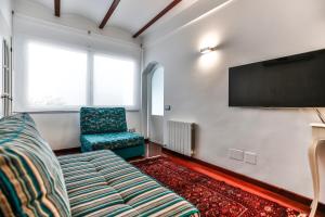 a room with a tv and a couch and a chair at Montroig Mar in Sitges
