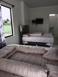 two beds sitting in a room with a window at LA97 Homestay in Berastagi