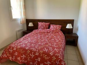 a bedroom with a bed with a red comforter and two lamps at Appartement 2 chambres in Prayssac +2 photos