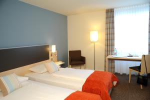 a hotel room with a bed and a desk at Mercure Bonn Hardtberg in Bonn