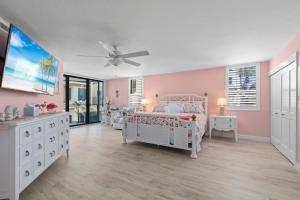 a bedroom with pink walls and a bed and a dresser at Pine Cove 104 in Sanibel +59 photos