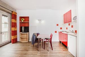 a kitchen with red cabinets and a table with chairs at Appart Hôtel Avy Baudelaire - Lyon Bellecour in Lyon