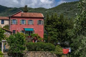 Ein rotes Haus vor einem Berg im Hintergrund in der Unterkunft Ca' Roscia in Dolcedo