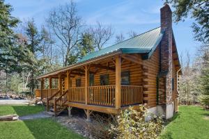 a log cabin with a porch and a chimney at Moose Cabin in Bridgton