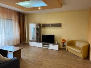 a living room with a flat screen tv and a chair at Central Lovely Apartment Craiova in Craiova