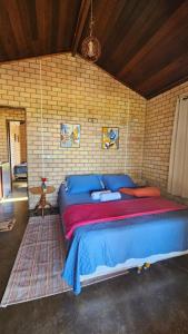 a bedroom with a large bed with blue and red sheets at Chalé Serra dos Matões 08 - Pedro II in Pedro II
