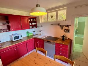 a kitchen with red cabinets and a table and a microwave at La Maison de la Rose in Étretat