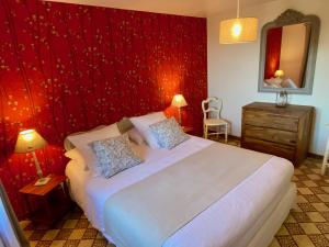 a bedroom with a large bed with a red wall at La Maison de la Rose in Étretat