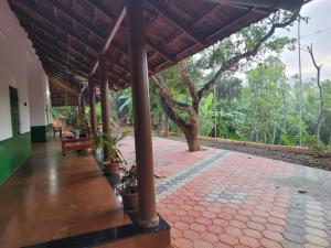 a porch of a house with a bench and trees at Ophel Ayurvedic Gardens, 7 Bed Heritage Home in Mananthavady +30 photos