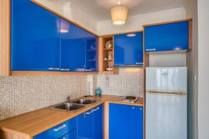 a blue kitchen with a sink and a refrigerator at Komi Shoreline Blue Window in Kómi