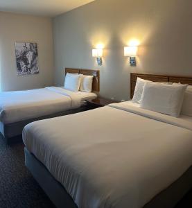 two beds in a hotel room with white sheets at The Sawmill Inn in Houston