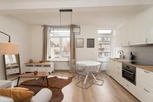 Una cocina y sala de estar con gabinetes blancos y una mesa. en Cozy apartement in the heart of Brussels, en Bruselas