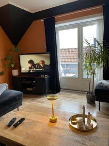 a living room with a flat screen tv and a table at Leilighet med sydvendt balkong in Ålesund