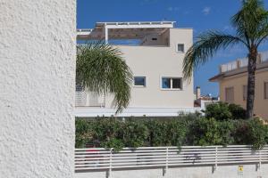 a white building with a palm tree in front of it at Dimora Nesea in Cozze