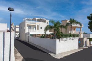 a white house with palm trees in front of it at Dimora Nesea in Cozze