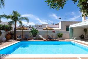 a pool with chairs and umbrellas next to a house at Dimora Nesea in Cozze