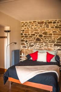 a bedroom with a stone wall and a bed with red pillows at Lodge de La Vallée in Saint-Rémy