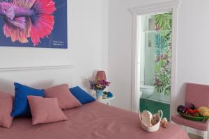 a bedroom with a bed with pink and blue pillows at Dimora Nesea in Cozze