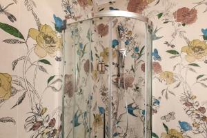 a shower in a bathroom with floral wallpaper at Dimora Nesea in Cozze