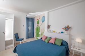 a bedroom with a blue bed with pink and green pillows at Dimora Nesea in Cozze