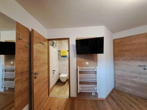 a bathroom with a toilet and a television on the wall at Apartment Daniela-7 by Interhome in Niederau