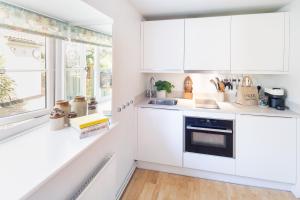 eine Küche mit weißen Schränken und einem Fenster in der Unterkunft Tranquil 2 bed cottage Sidmouth, rural escape in Salcombe Regis + 17 Fotos