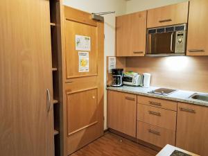 a small kitchen with wooden cabinets and a microwave at Apartment Rosa-8 by Interhome in Mayrhofen