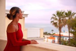 a woman in a red dress looking out over a ledge at Dimora Nesea in Cozze