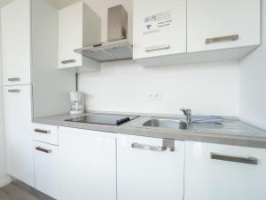 eine weiße Küche mit einem Waschbecken und weißen Schränken in der Unterkunft Holiday Home New Dahlia 1 by Interhome in Bredene