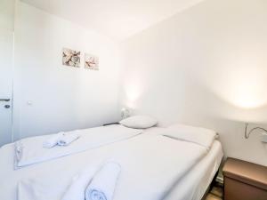 ein weißes Bett mit weißer Bettwäsche und Handtüchern darauf in der Unterkunft Holiday Home New Dahlia 1 by Interhome in Bredene