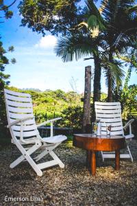 two white chairs and a table and a chair at Casa do Pico in Santo Antônio do Pinhal