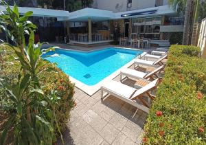 Una piscina con tumbonas al lado de un edificio. en Vallclaire Suites, en Barranquilla