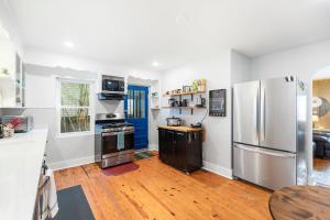 a kitchen with a refrigerator and a wooden floor at The Bungle House - Funky Bungalow in Charleston