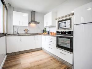 Una cocina blanca con gabinetes blancos y un microondas. en Apartment Rinconada beachfront 2 by Interhome, en Rincón de la Victoria