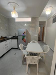 una cucina con tavolo e sedie bianchi e frigorifero di Oasis Aglou a Aglou