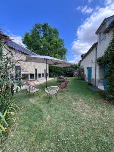 a patio with two chairs and a table with an umbrella at Magnifique Refuge avec piscine et animaux situé au coeur des châteaux de la Loire et des vignobles in Cinais